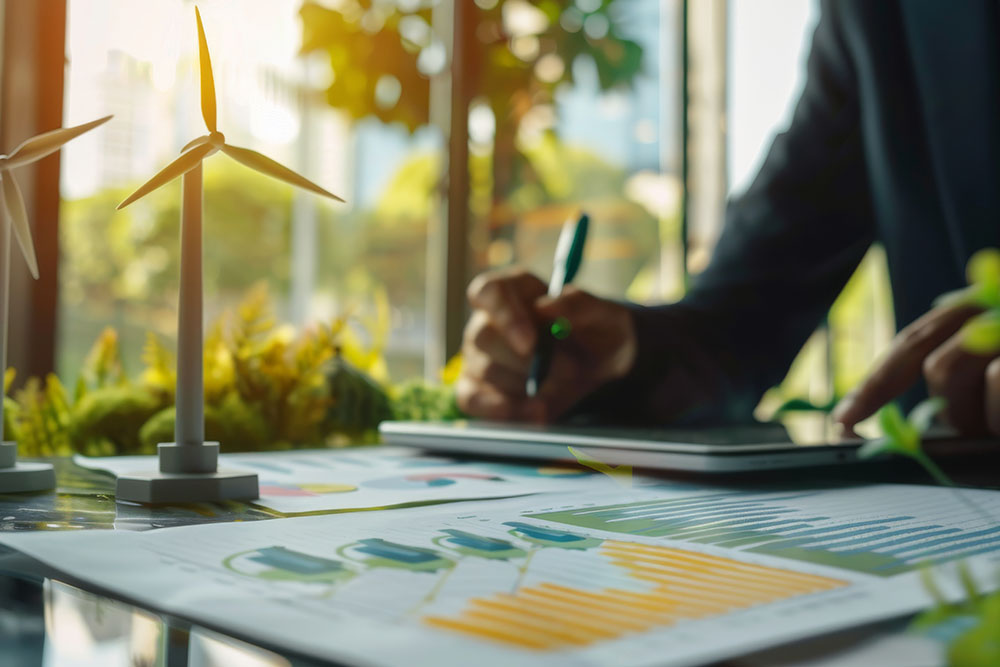 Hand schreibt auf Tablet. Modell eines Windrad auf Tisch